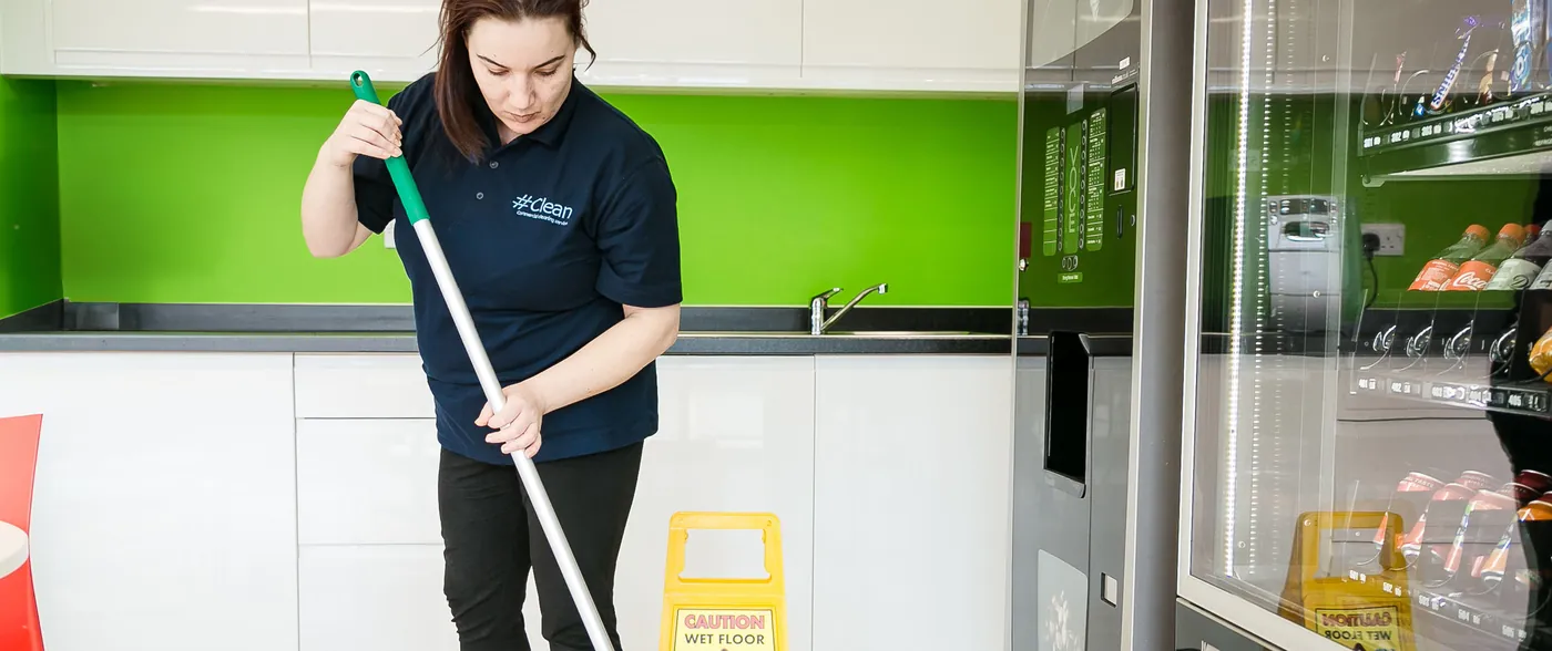 Cleaner mopping an office kitchen to reduce health risks in office environments