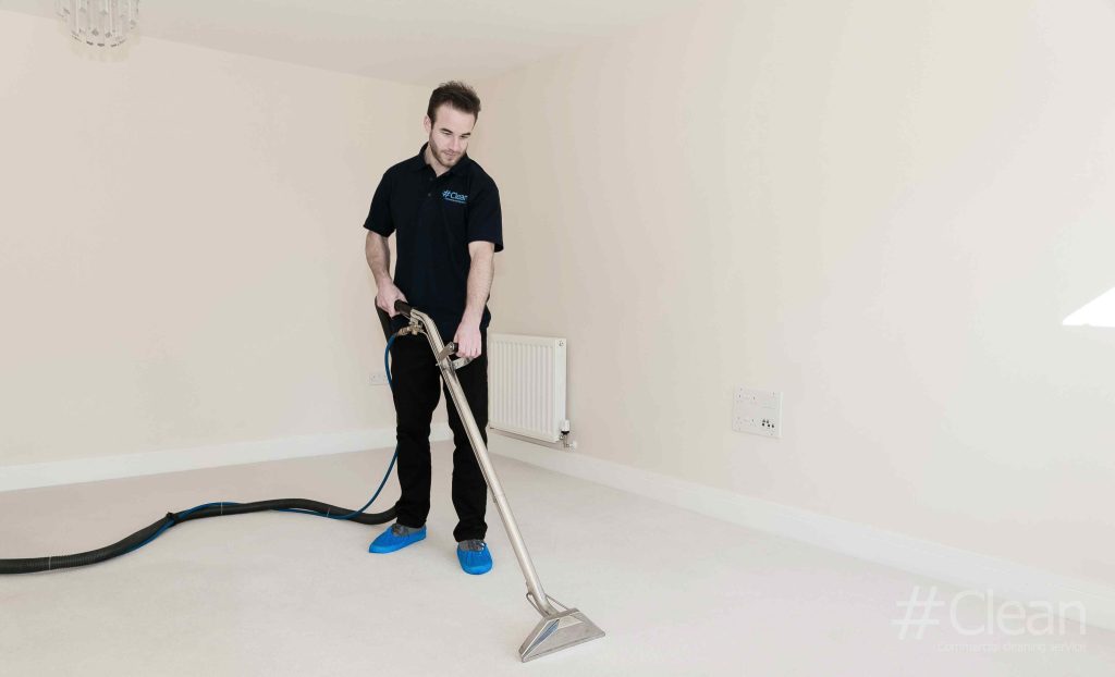 man in hashtag clean uniform cleaning a carpet