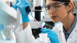 Female lab technician using a pipette to test a sample in a laboratory setting