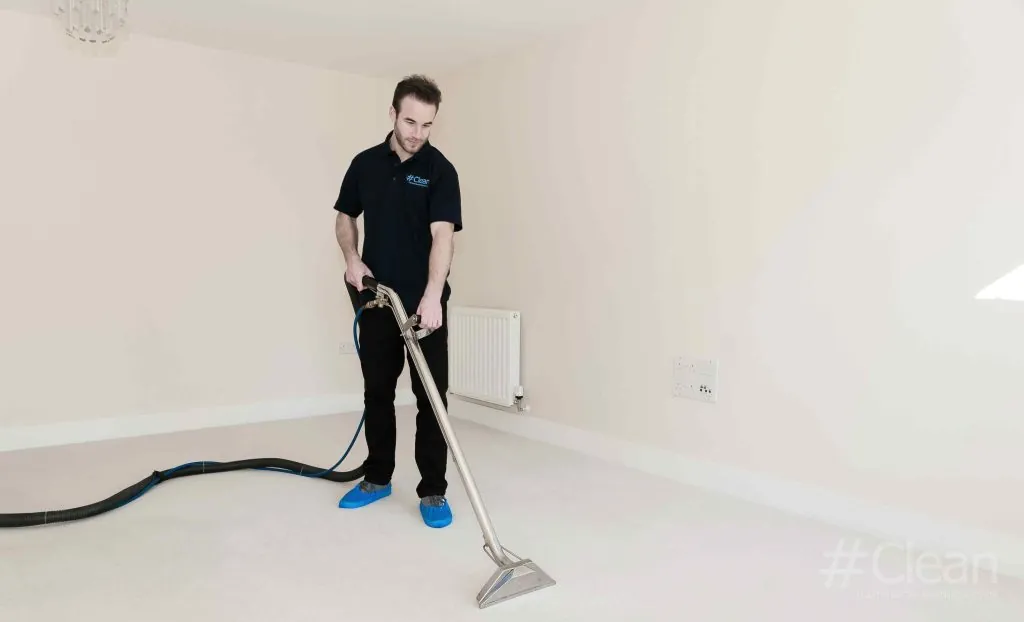 man in hashtag clean uniform cleaning a carpet