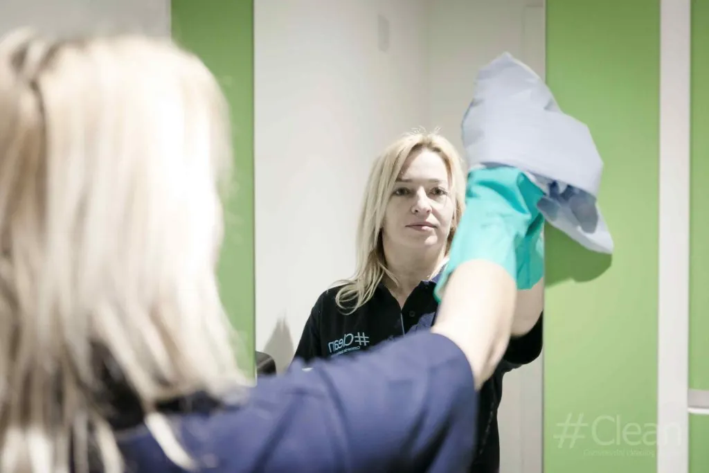 a woman wiping a bathroom mirror