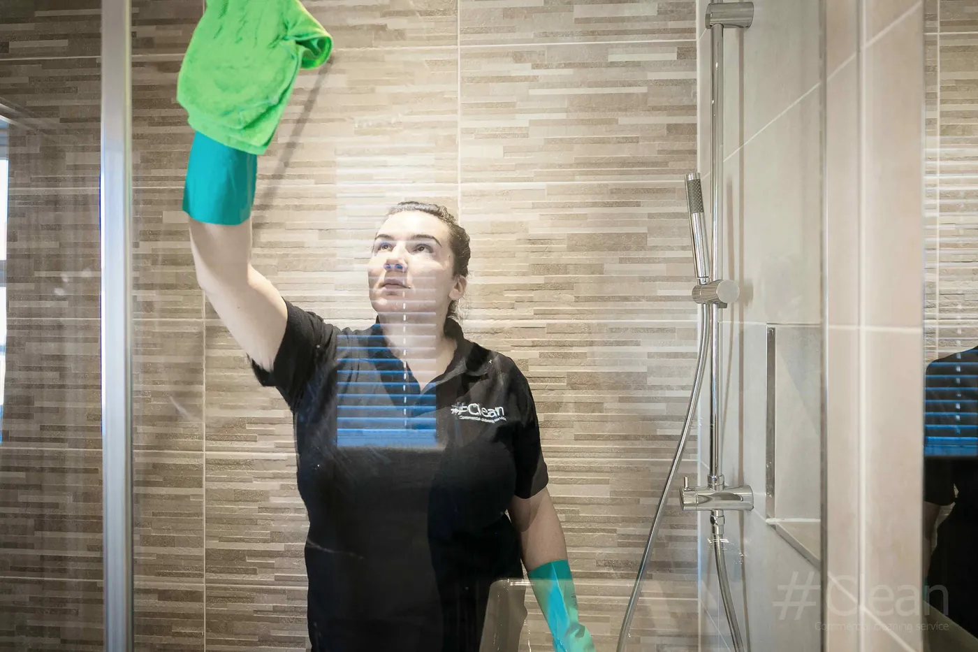 Woman cleaning the inside of a glass shower pane in Maidstone