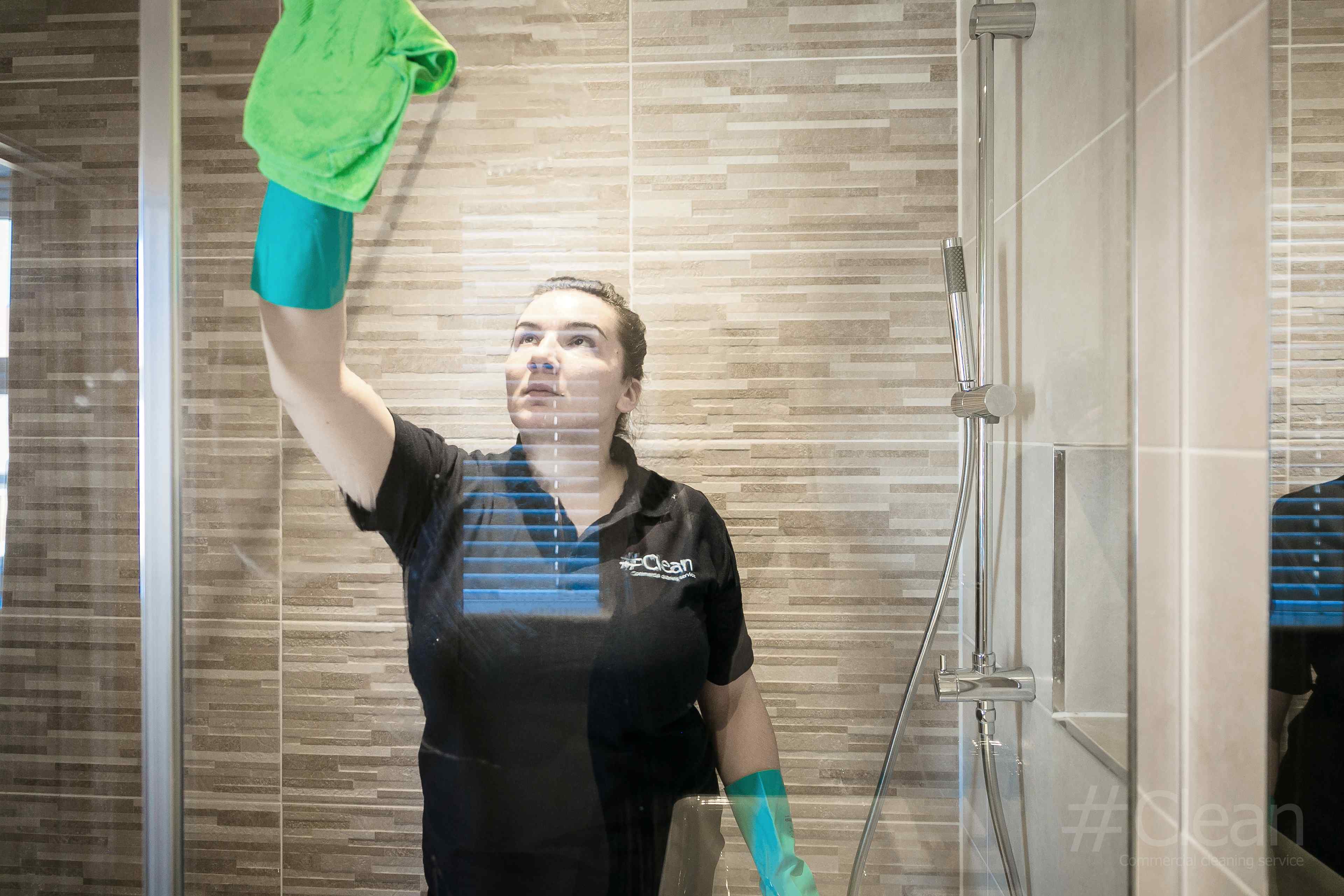Woman Cleaning The Inside Of A Glass Shower Pane