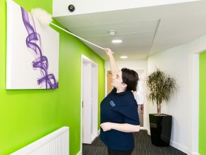 Cleaner dusting high surfaces to prevent hidden health risks in office environments