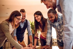 Smiling office team collaborating around a desk during a team meeting in a modern workplace working in clean office